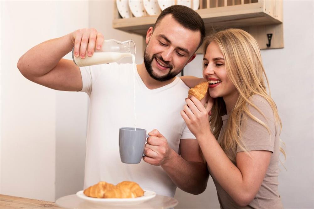 man-woman-pouring-milk-eating-croissants