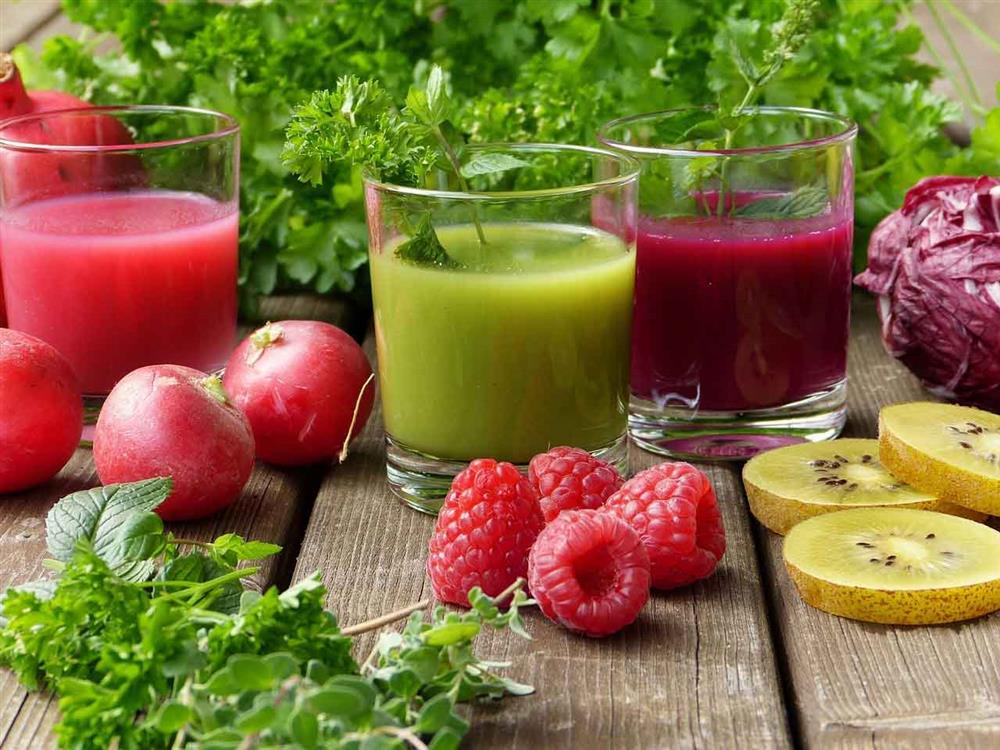 Three glasses of fruit juice with fruits and vegetables around them